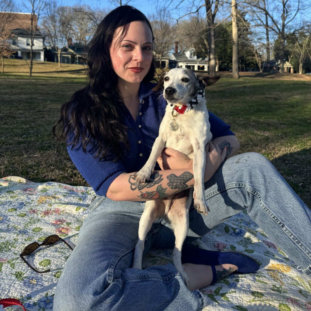Olivia is holding her pup at a park.